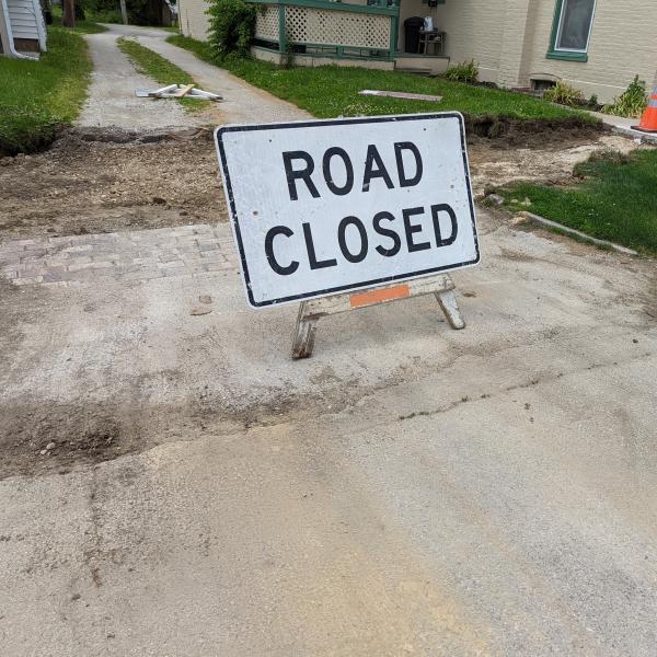 A white signs indicates that a road is being closed for construction